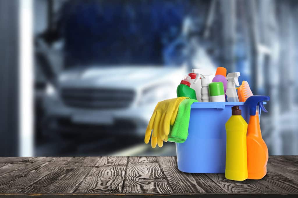 Bucket with cleaning supplies on wooden surface at car wash.